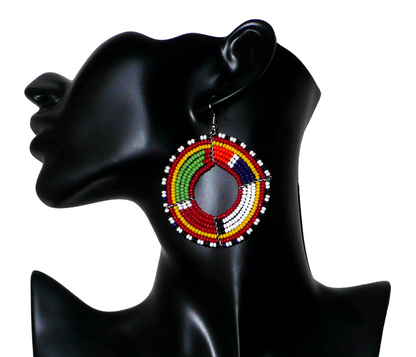 Bijoux ethniques. Boucles d'oreilles africaines de tradition ethnique Massai faites de perles de rocaille rouges et multicolores enfilées sur sept rangées de fils de fer montés en forme de cercles. Elles mesurent 7,5 cm de long et 5,5 cm de large. Les boucles d'oreilles sont ici photographiées sur un mannequin. Timeless Fineries