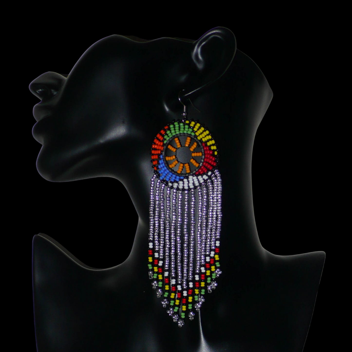 Longues boucles d'oreilles sud-africaines traditionnelles à franges et motifs zoulous composées de perles de rocaille gris clair translucides et multicolores. Elles mesurent 14,5 cm de long et 4,5 cm de large, et elles se portent avec des crochets en acier inoxydable sur des oreilles percées.