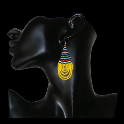 Boucles d'oreilles africaines traditionnelles zouloues en forme de gouttes composées d'un tissage de perles de rocaille jaunes et multicolores. Elles mesurent 7 cm de long et 2,5 cm de large et se portent sur des oreilles percées.