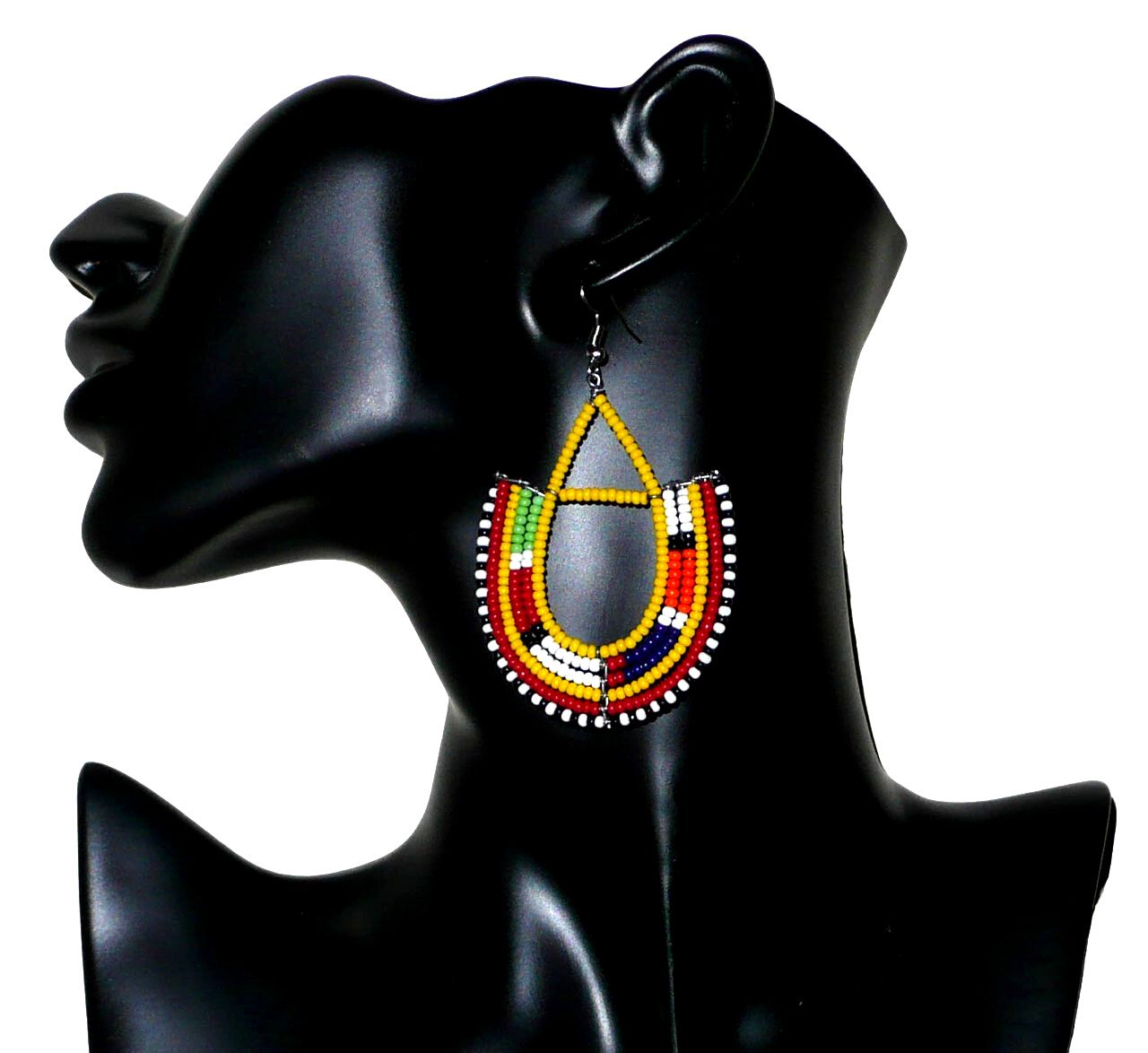 Bijoux africains Massai. Boucles d'oreilles africaines à motifs traditionnels Massai composées de perles de rocaille jaunes et multicolores enfilées sur des fils de fer montés en forme d'ancres . Elles mesurent 7,5 cm de long et 4,5 cm de large et se portent avec des crochets en acier inoxydable sur des oreilles percées. Elles sont sur cette photo présentées sur un mannequin. Timeless Fineries