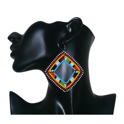 Longues et larges boucles d'oreilles africaines de tradition Massai en perles de rocaille multicolores. Elles mesurent 8.5 cm de long et 7 cm de large et se portent sur des oreilles percées.
