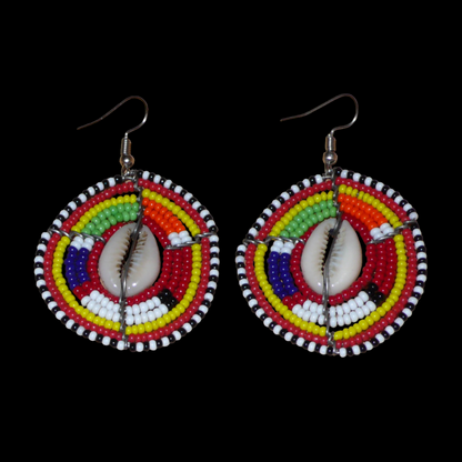 Boucles d'oreilles africaines traditionnelles en forme de boucliers Massai composées de perles de rocaille rouges et multicolores et de coquillages. De taille moyenne, elles mesurent 6 cm de long et 4 cm de large, et se portent avec des crochets en acier inoxydable sur des oreilles percées.