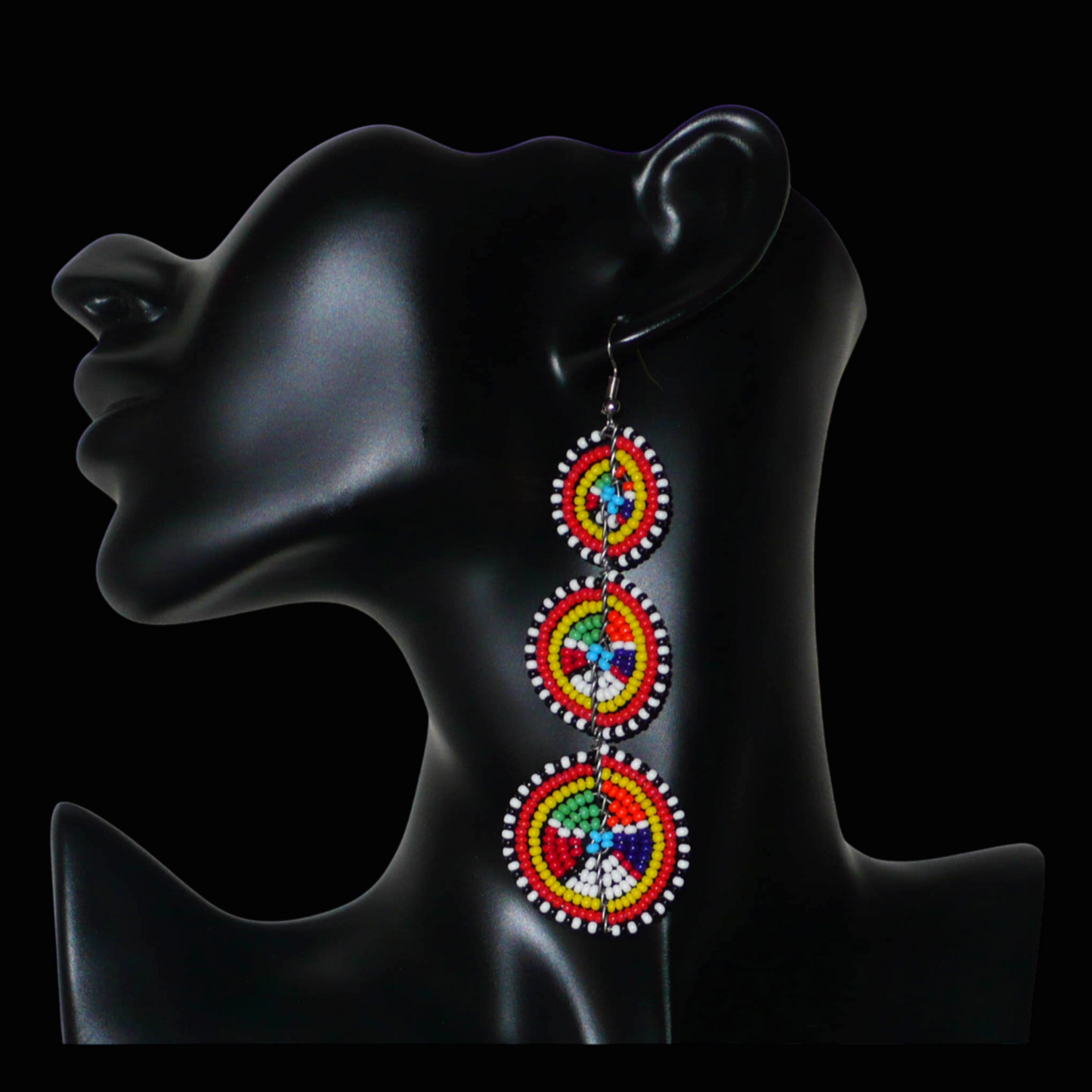 Ajoutez une note colorée évoquant le style ethnique afro chic des années 70 à votre look, avec cette paire de boucles d'oreilles africaines traditionnelles de confection artisanale Massai. Elles se composent de perles de rocaille multicolores glissées sur des fils de fer montés en forme de trois cercles superposés. Ces boucles d'oreilles mesurent 10.5 cm de long et 3 cm de large, et elles se portent avec des crochets en acier inoxydable sur des oreilles percées. 
