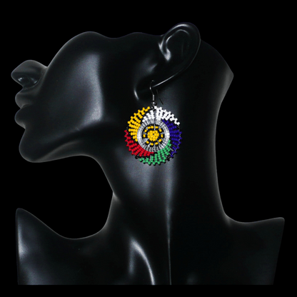 Boucles d'oreilles sud-africaines rondes à motifs traditionnels zoulous composées de perles de rocaille multicolores. Elles mesurent 5.5 cm de long et 4 cm de large, et se portent sur des oreilles percées.