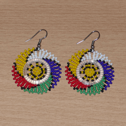 Boucles d'oreilles sud-africaines rondes à motifs traditionnels zoulous composées de perles de rocaille multicolores. Elles mesurent 5.5 cm de long et 4 cm de large, et se portent sur des oreilles percées.