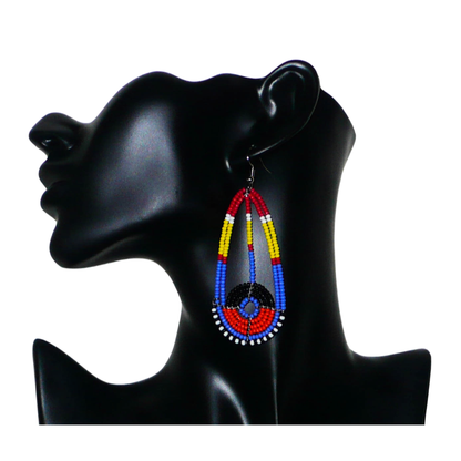 Longues boucles d'oreilles ethniques afro chic de tradition Massai composées de perles de rocaille multicolores. Elles mesurent 8.5 cm de long et 3.5 cm de large et se portent sur des oreilles percées.