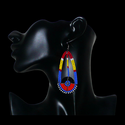 Longues boucles d'oreilles ethniques afro chic de tradition Massai composées de perles de rocaille multicolores. Elles mesurent 8.5 cm de long et 3.5 cm de large et se portent sur des oreilles percées.