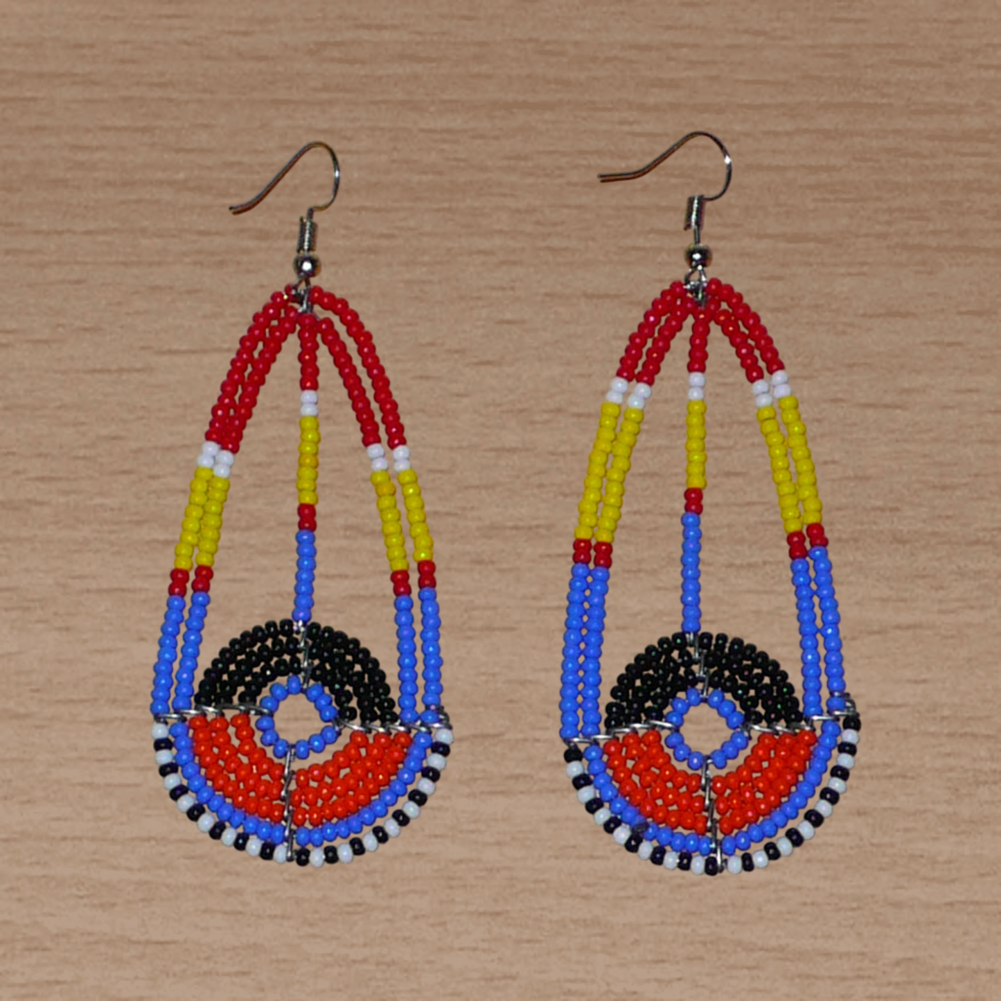 Longues boucles d'oreilles ethniques afro chic de tradition Massai composées de perles de rocaille multicolores. Elles mesurent 8.5 cm de long et 3.5 cm de large et se portent sur des oreilles percées.