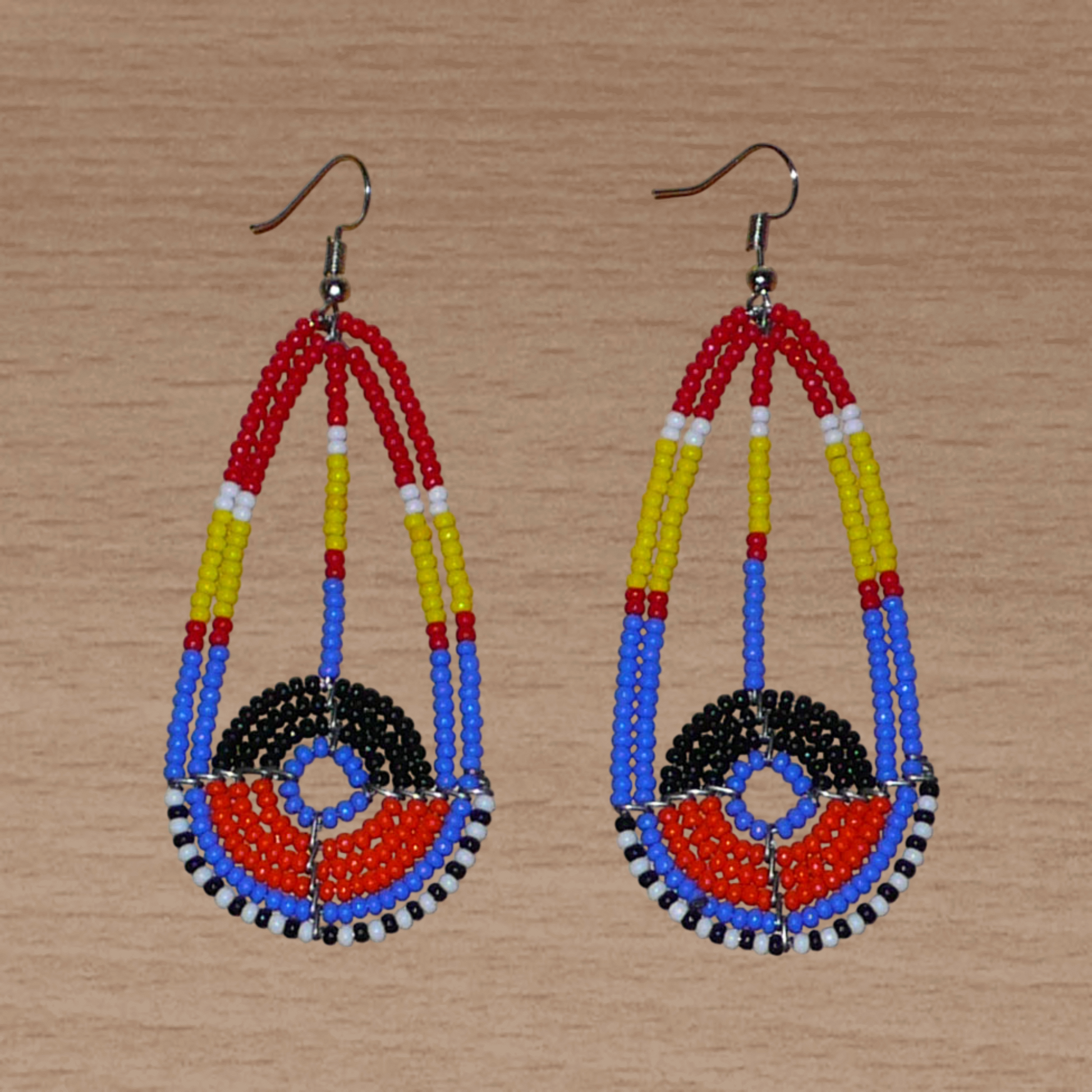 Longues boucles d'oreilles ethniques afro chic de tradition Massai composées de perles de rocaille multicolores. Elles mesurent 8.5 cm de long et 3.5 cm de large et se portent sur des oreilles percées.
