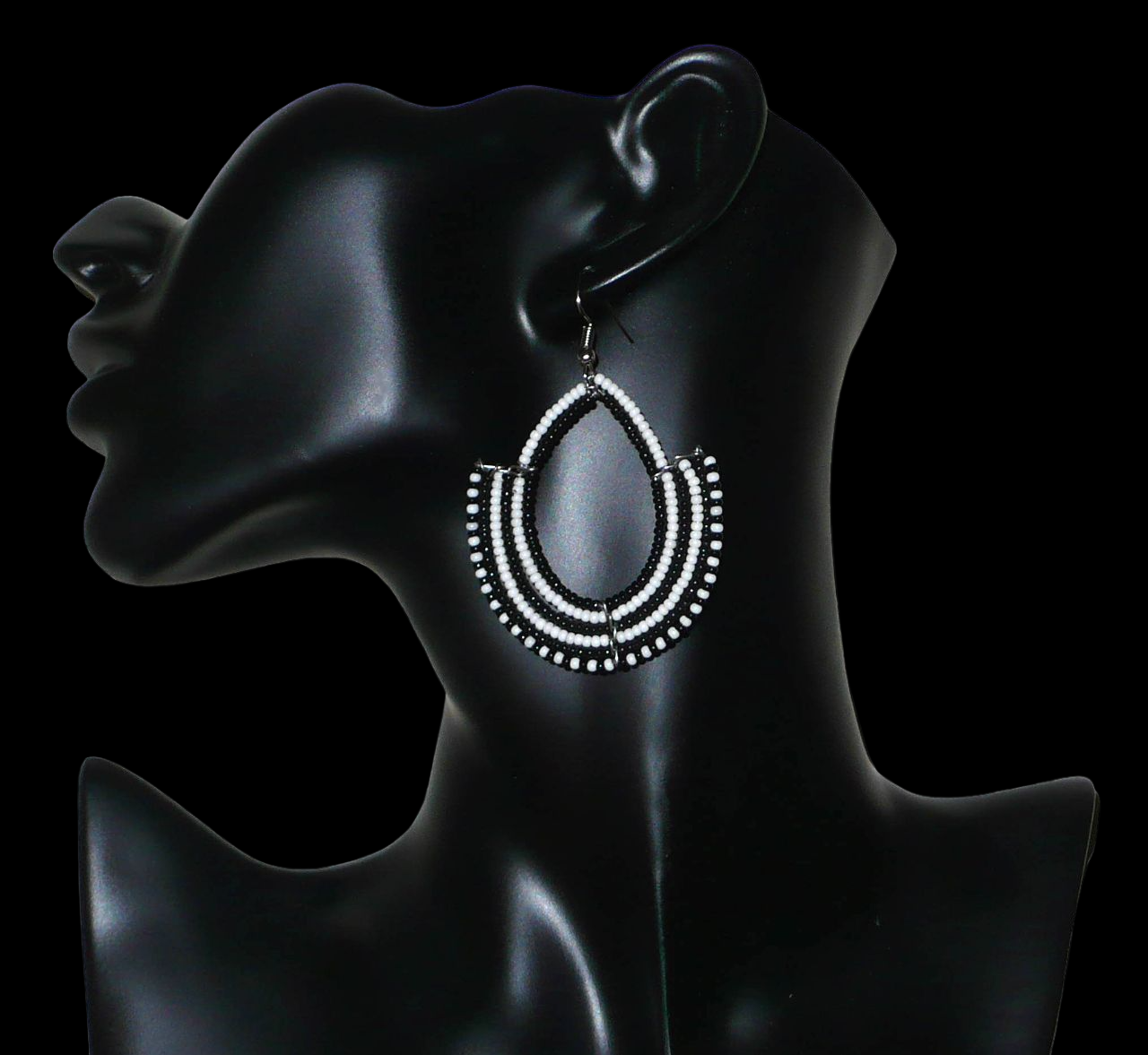 Boucles d'oreilles ethniques bicolores composées de perles de rocaille noires et blanches glissées sur des structures en fils de fer montés en forme d'ancres. Elles mesurent 7 cm de long et 4,5 cm de large et se portent sur des oreilles percées.