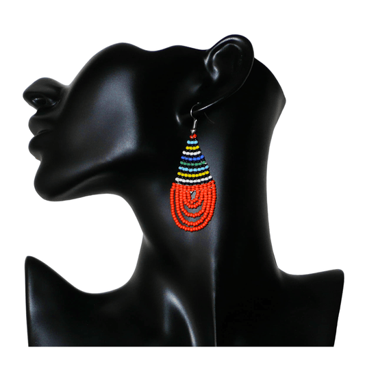 Boucles d'oreilles africaines en forme de gouttes faites de perles de rocaille orange et multicolores. Elles mesurent 7 cm de long et 2,5 cm de large, et se portent sur des oreilles percées.