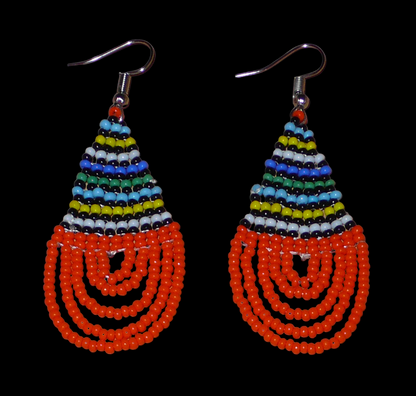 Boucles d'oreilles africaines en forme de gouttes faites de perles de rocaille orange et multicolores. Elles mesurent 7 cm de long et 2,5 cm de large, et se portent sur des oreilles percées.