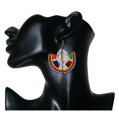 Apportez une touche de couleur et d'authenticité à votre style avec cette paire de boucles d'oreilles africaines issues de l'artisanat traditionnel Massai. Confectionnées à la main au Kenya, ces boucles d'oreilles ethniques se composent de perles de rocaille blanches et multicolores et de coquillages cauris. De taille moyenne, elles mesurent 6 cm de long et 4.5 cm de large, et se portent avec des crochets en acier inoxydable sur des oreilles percées.