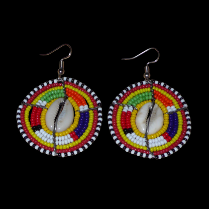 Ambiance exotique avec ces jolies boucles d'oreilles africaines à motifs ethniques traditionnels Massai de conception artisanale kenyane. Elles sont composées de perles de rocaille jaunes et multicolores et de coquillages cauris fixés sur des fils de fer montés en forme de boucliers Massai. Ces boucles d'oreilles de taille moyenne mesurent 6.5 cm de long et 4 cm de large ; elles se portent avec des crochets en acier inoxydable sur des oreilles percées.