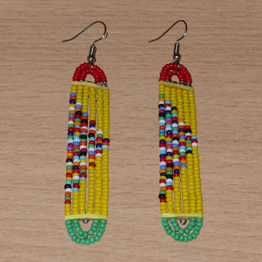 Longues boucles d'oreilles africaines aux accents exotiques composées de perles jaunes, rouges, vertes et multicolores montées en forme de rectangles aux bouts arrondis. Elles mesurent 9 cm de long et 1.5 cm de large, et se portent avec des crochets en acier inoxydable sur des oreilles percées.
