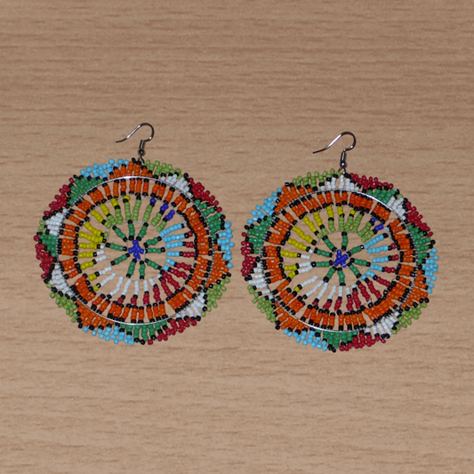 Boucles d'oreilles africaines surdimensionnées aux motifs traditionnels zoulous et couleurs rétro évoquant le style afro chic des années 70 : elles se composent de perles de rocaille multicolores et mesurent 10 cm de long et 8.5 cm de large ; elles se portent avec des crochets en acier inoxydable sur des oreilles percées.