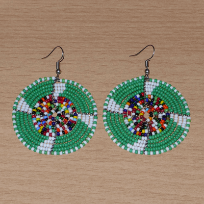 Ajoutez une touche ethnique afro bohème à votre look avec ces boucles d'oreilles africaines rondes confectionnées à la main dans la tradition artisanale Massai : elles se composent de perles de rocaille principalement vertes, puis blanches et multicolores glissées sur des structures circulaires en fils de fer.
Cette paire de boucles d'oreilles mesure 6.5 cm de long et 4.5 cm de large, et se porte avec des crochets en acier inoxydable sur des oreilles percées.