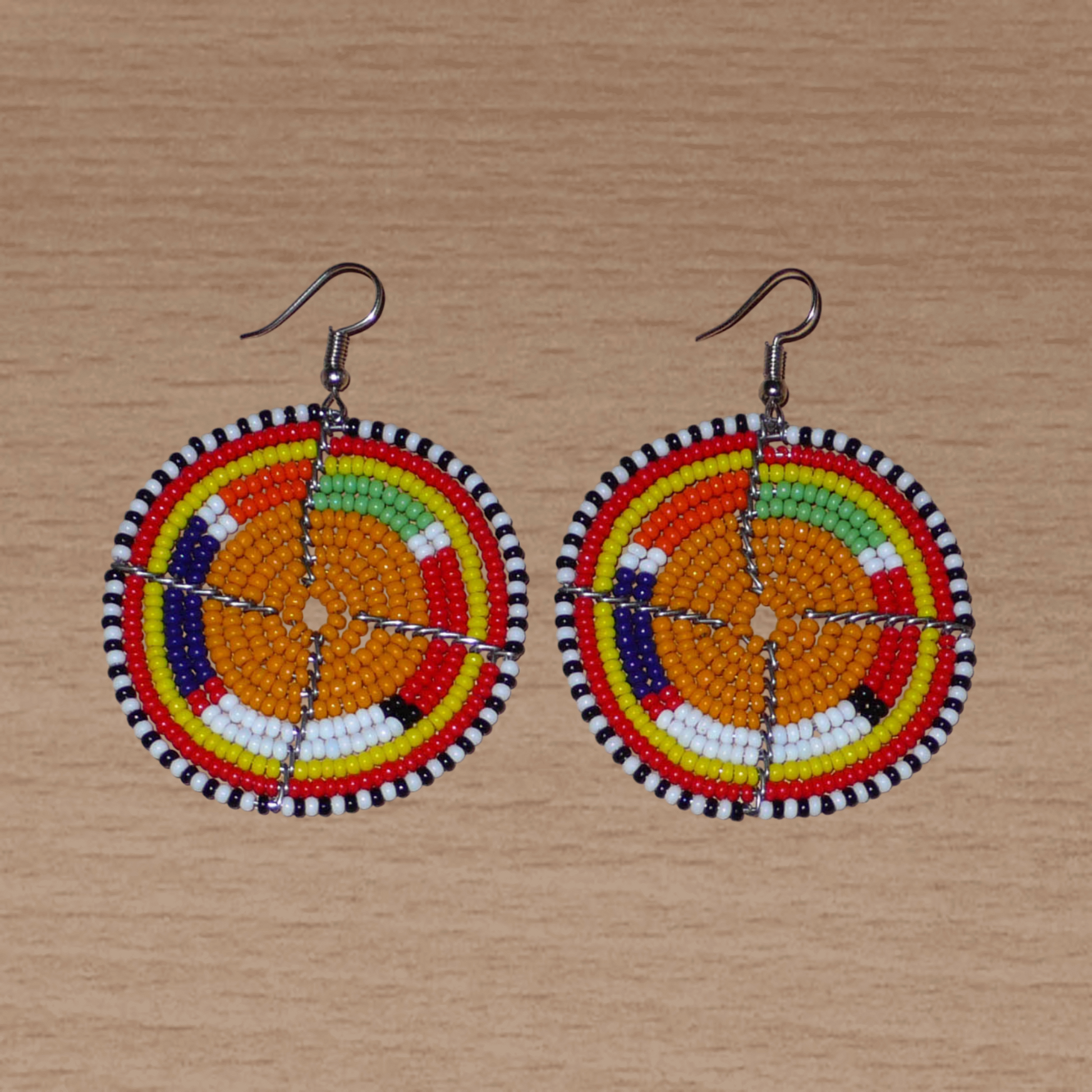 Boucles d'oreilles africaines Massai rondes fabriquées au Kenya, faites de perles de rocaille orange et multicolores. De taille moyenne, ces boucles d'oreilles mesurent 6,5 cm de long et 4,5 cm de large ; elles se portent avec des crochets en acier inoxydable sur des oreilles percées.