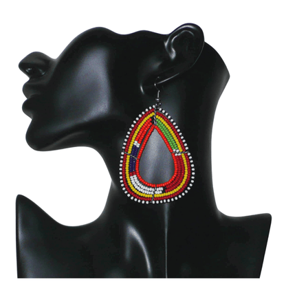 Boucles d'oreilles africaines traditionnelles à motifs ethniques Massai composées de perles de rocaille orange et multicolores enfilées sur six rangées de fils de fer montés en forme de triangles aux bords arrondis. Elles mesurent 8,5 cm de long et 5 cm de large et se portent avec des crochets en acier inoxydable sur des oreilles percées.