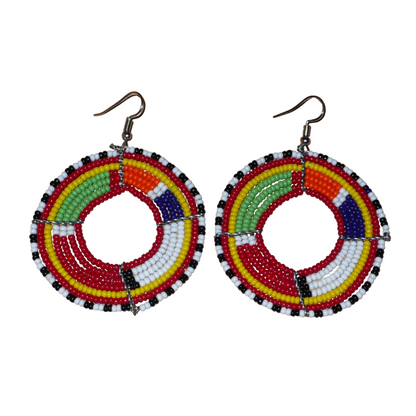 Boucles d'oreilles africaines rondes aux motifs et couleurs Massai composées de perles de rocaille rouges et multicolores enfilées sur sept rangées de fils de fer montés en forme de cercles. Elles mesurent 7,5 cm de long et 5,5 cm de large et se portent avec des crochets en acier inoxydable sur des oreilles percées.