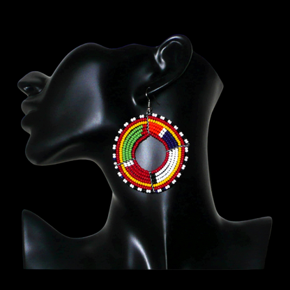 Boucles d'oreilles africaines rondes aux motifs et couleurs Massai composées de perles de rocaille rouges et multicolores enfilées sur sept rangées de fils de fer montés en forme de cercles. Elles mesurent 7,5 cm de long et 5,5 cm de large et se portent avec des crochets en acier inoxydable sur des oreilles percées.
