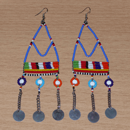 Boucles d'oreilles africaines Massai composées de perles de rocaille bleues et multicolores et de perles en plastique enfilées sur des structures à formes géométriques en fils de fer, et se prolongent de chaînettes décorées de disques métalliques. Surdimensionnées, elles mesurent 14.5 cm de long et se portent sur des oreilles percées.