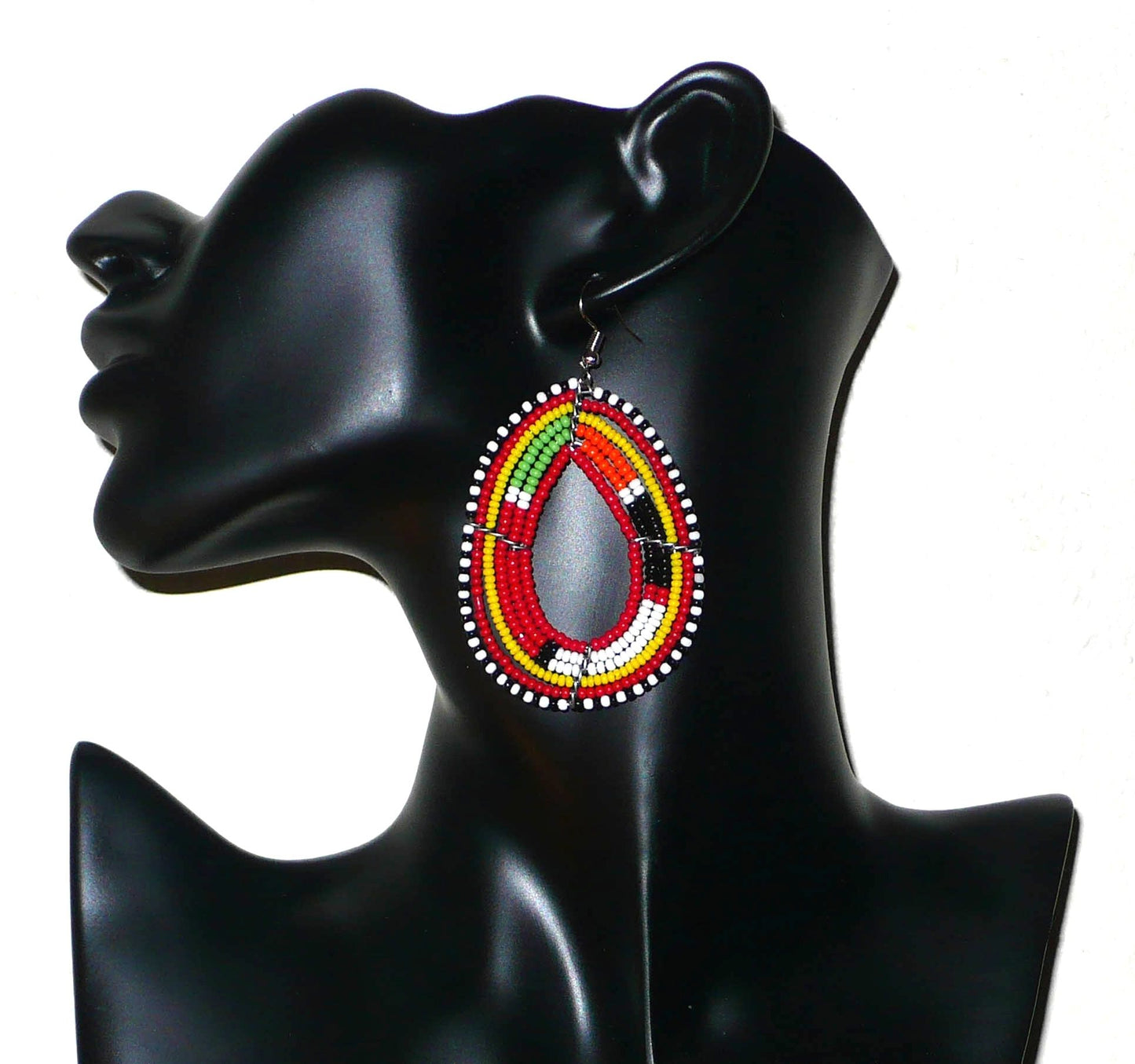 Boucles d'oreilles africaines aux motifs traditionnels Massai composées de perles de rocaille rouges et multicolores enfilées sur des fils de fer montés en forme de gouttes. Elles mesurent 7,5 cm de long et 4 cm de large et se portent avec des crochets en acier inoxydable.