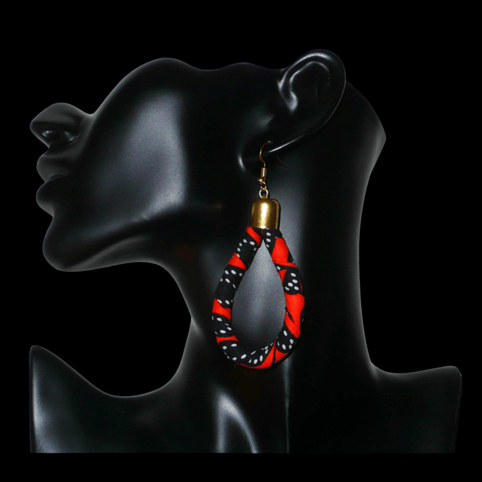 Longues boucles d'oreilles africaines tubulaires en forme de gouttes composées de bandes de tissu africain orange et noir avec des touches de blanc. Elles mesurent 9 cm de long et 4 cm de large et se portent avec des crochets en acier inoxydable sur des oreilles percées.