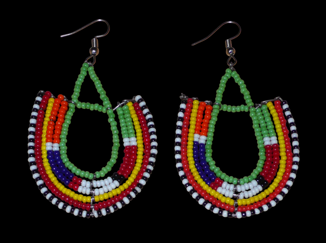 Boucles d'oreilles ethniques en forme d'ancres, confectionnées à la main par des artisans passionnés, composées de perles de rocaille vertes et multicolores glissées sur des structures géométriques en fils de fer. Elles mesurent 7.5 cm de long et 4.5 cm de large et se portent avec des crochets en acier inoxydable sur des oreilles percées. 