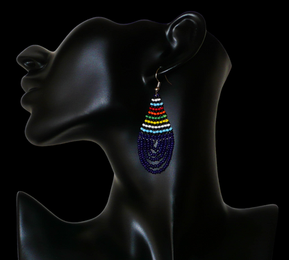 Boucles d'oreilles africaines traditionnelles zouloues en forme de gouttes composées de perles de rocaille bleu foncé et multicolores. Elles mesurent 7 cm de long et 2.5 cm de large, et se portent sur des oreilles percées.
