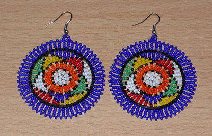 Boucles d'oreilles sud-africaines rondes à motifs ethniques zoulous composées de perles de rocaille bleues et multicolores. Elles mesurent 7,5 cm de long et 5,5 cm de large et se portent avec des crochets en acier inoxydable sur des oreilles percées.