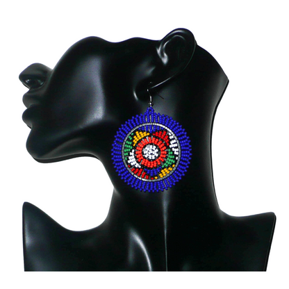 Boucles d'oreilles sud-africaines rondes à motifs ethniques zoulous composées de perles de rocaille bleues et multicolores. Elles mesurent 7,5 cm de long et 5,5 cm de large et se portent avec des crochets en acier inoxydable sur des oreilles percées.