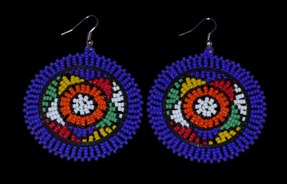 Boucles d'oreilles africaines rondes à motifs ethniques sud-africains composées de perles de rocaille bleues et multicolores. Elles mesurent 7,5 cm de long et 5,5 cm de large et se portent avec des crochets en acier inoxydable sur des oreilles percées. Timeless Fineries