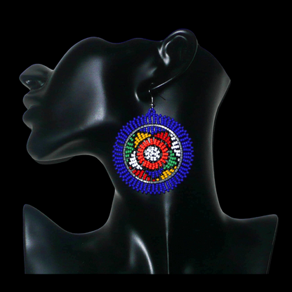Boucles d'oreilles sud-africaines rondes à motifs ethniques zoulous composées de perles de rocaille bleues et multicolores. Elles mesurent 7,5 cm de long et 5,5 cm de large et se portent avec des crochets en acier inoxydable sur des oreilles percées.