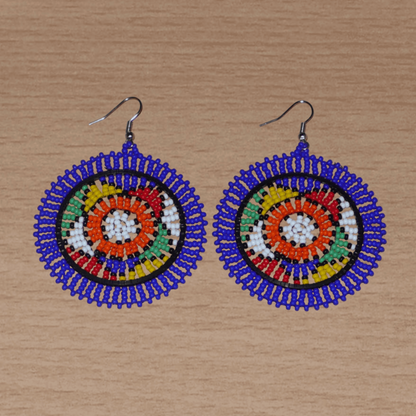 Boucles d'oreilles sud-africaines rondes à motifs ethniques zoulous composées de perles de rocaille bleues et multicolores. Elles mesurent 7,5 cm de long et 5,5 cm de large et se portent avec des crochets en acier inoxydable sur des oreilles percées.