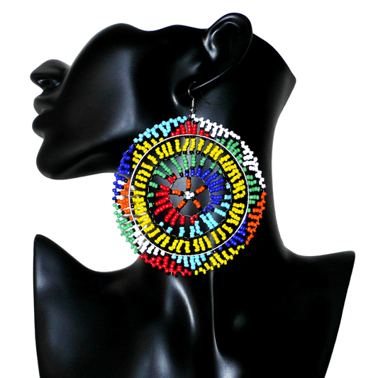 Boucles d'oreilles sud-africaines rondes au style afro chic des années 70. Elles se composent de perles de rocaille multicolores enfilées sur des fils de nylon fixés sur des structures circulaires. Surdimensionnées, elles mesurent 10 cm de long et 8,5 cm de large, et se portent sur des oreilles percées.