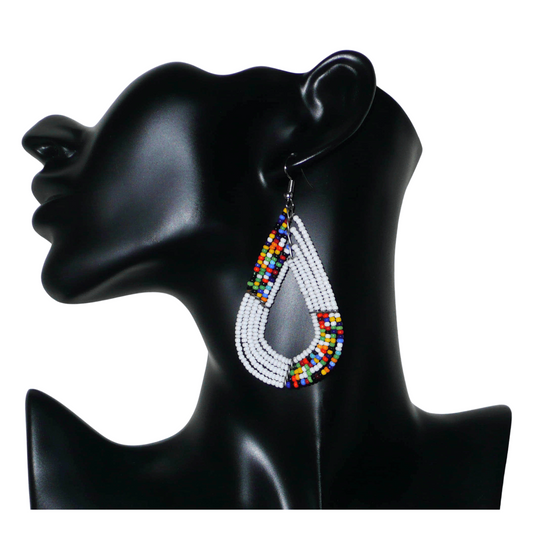 Boucles d'oreilles africaines multi-rangs blanches et multicolores aux accents évoquant le style bohème des années 70. Fabriquées au Kenya, elles se composent de perles de rocaille blanches et d'un mélange de perles multicolores glissées sur cinq rangées de fils de fer en forme de gouttes légèrement triangulaires. Ces boucles d'oreilles mesurent 8 cm de long et 4 cm de large ; elles se portent avec des crochets en acier inoxydable sur des oreilles percées.
