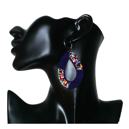 Boucles d'oreilles afro bohème bleu marine et multicolores en forme de gouttes composées de perles de rocaille. Elles mesurent 7,5 cm de long et 4 cm de large, et se portent sur des oreilles percées.