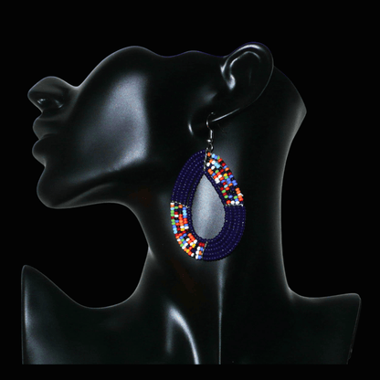 Boucles d'oreilles afro bohème bleu marine et multicolores en forme de gouttes composées de perles de rocaille. Elles mesurent 7,5 cm de long et 4 cm de large, et se portent sur des oreilles percées.
