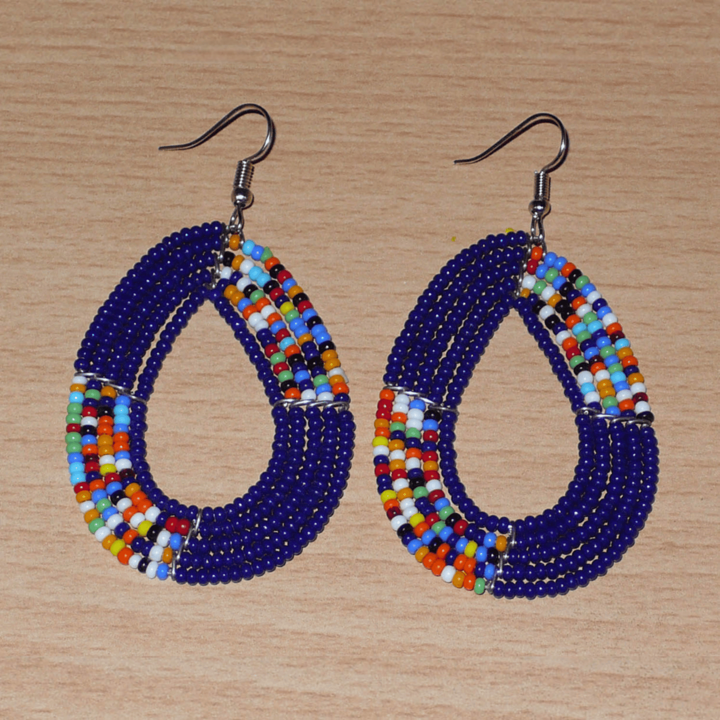 Boucles d'oreilles afro bohème bleu marine et multicolores en forme de gouttes composées de perles de rocaille. Elles mesurent 7,5 cm de long et 4 cm de large, et se portent sur des oreilles percées.