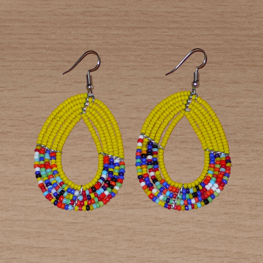 Boucles d'oreilles multi-rangs jaunes et multicolores faites de perles de rocaille enfilées sur cinq rangées de fils de fer montés en forme de gouttes. Elles mesurent 7 cm de long et 3,5 cm de large et se portent sur des oreilles percées.
