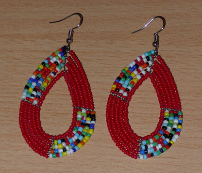 Boucles d'oreilles kenyanes multi-rangs rouges et multicolores composées de perles de rocaille montées en forme de gouttes. Elles mesurent 8 cm de long et 4 cm de large et se portent sur des oreilles percées.