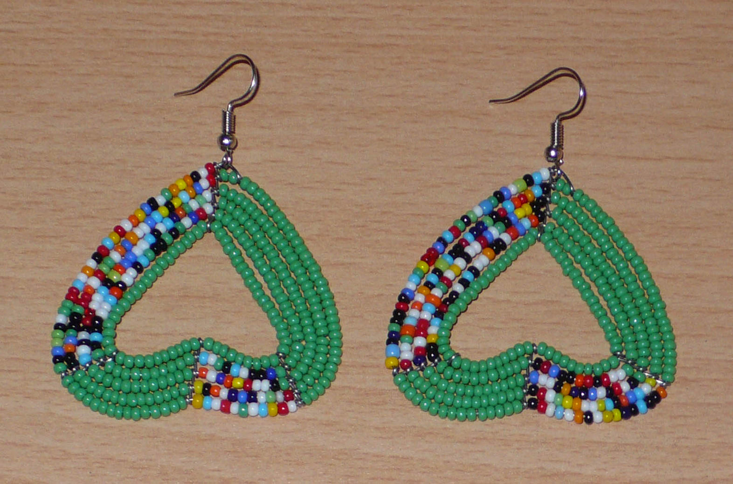Boucles d'oreilles afro bohème vertes et multicolores composées de perles de rocaille montées en forme de cœurs inversés.