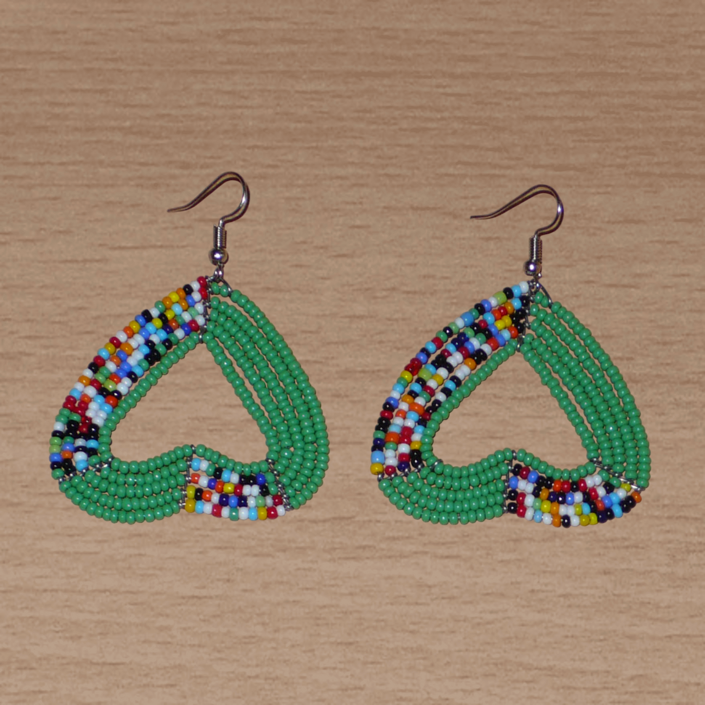 Boucles d'oreilles afro bohème vertes et multicolores composées de perles de rocaille montées en forme de cœurs inversés.