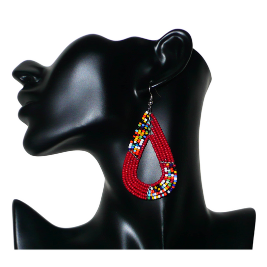 Boucles d'oreilles africaines Massai rouges et multicolores aux accents évoquant le style boho chic des années 70. Confectionnées au Kenya, elles se composent de perles de rocaille rouges et d'un mélange de perles multicolores glissées sur cinq rangées de fils de fer en forme de gouttes légèrement triangulaires. Ces boucles d'oreilles mesurent 8 cm de long et 4 cm de large ; elles se portent avec des crochets en acier inoxydable sur des oreilles percées.