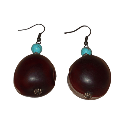 Boucles d'oreilles exotiques composées de graines tropicales ("Œil de bœuf") et de perles turquoises et dorées. Assez lourdes et de taille moyenne, ces boucles d'oreilles mesurent 6 cm de long et 3 cm de large ; elles se portent avec des crochets en acier inoxydable sur des oreilles percées.
