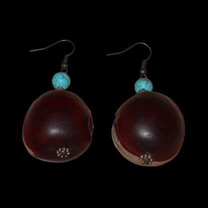 Boucles d'oreilles exotiques composées de graines tropicales ("Œil de bœuf") et de perles turquoises et dorées. Assez lourdes et de taille moyenne, ces boucles d'oreilles mesurent 6 cm de long et 3 cm de large ; elles se portent avec des crochets en acier inoxydable sur des oreilles percées.