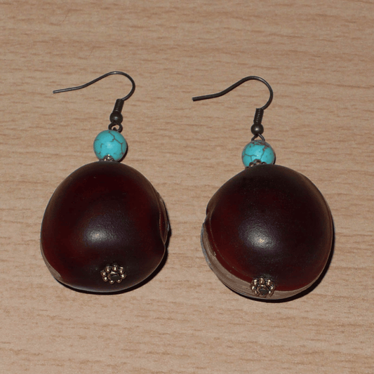 Boucles d'oreilles exotiques composées de graines tropicales ("Œil de bœuf") et de perles turquoises et dorées. Assez lourdes et de taille moyenne, ces boucles d'oreilles mesurent 6 cm de long et 3 cm de large ; elles se portent avec des crochets en acier inoxydable sur des oreilles percées.