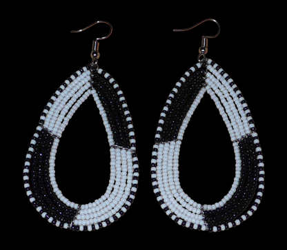 Longues boucles d'oreilles kenyanes en perles de rocaille blanches et noires enfilées sur plusieurs rangées de fils de fer montés en forme de gouttes. Ces boucles d'oreilles bicolores mesurent 8 cm de long et 4 cm de large et se portent avec des crochets en acier inoxydable sur des oreilles percées.