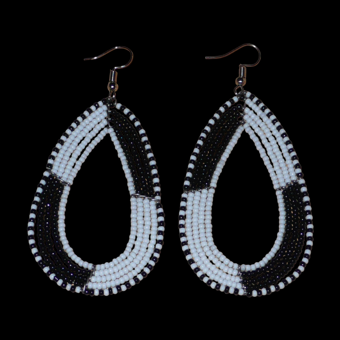 Longues boucles d'oreilles kenyanes en perles de rocaille blanches et noires enfilées sur plusieurs rangées de fils de fer montés en forme de gouttes. Ces boucles d'oreilles bicolores mesurent 8 cm de long et 4 cm de large et se portent avec des crochets en acier inoxydable sur des oreilles percées.